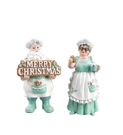 A Christmas figurine set featuring a Santa Claus figure holding a 'MERRY CHRISTMAS' sign and an older woman figure in a mint green and white apron, both on a plain white background.