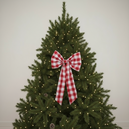 Decorated Christmas tree with a red and white checkered bow against a plain background