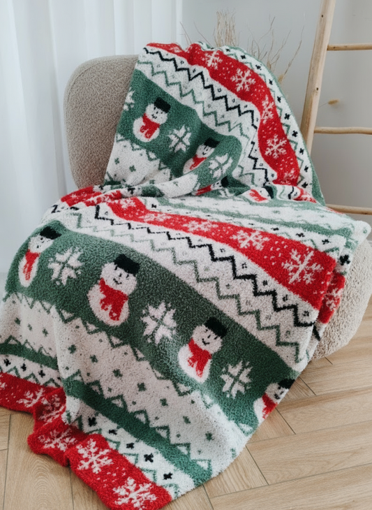 Christmas-themed blanket with snowmen and zigzag patterns on a chair.