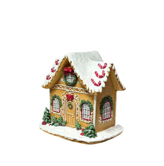 A gingerbread house Christmas ornament with a white snow-dusted roof and base, decorated with red candy canes, green wreaths, and a red bow on the door, shown on a plain white background.
