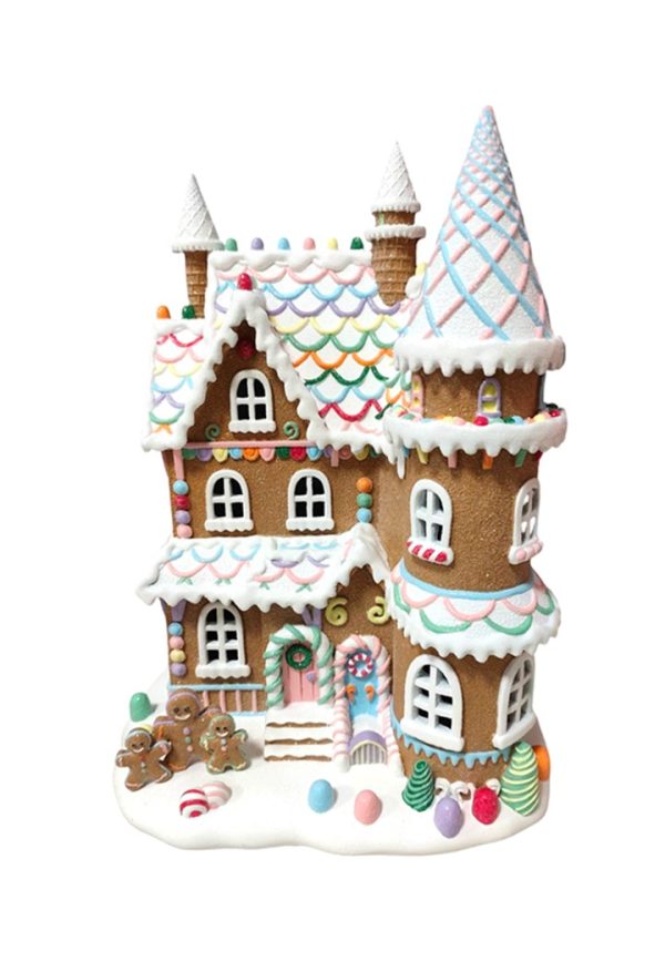 A gingerbread-style holiday house ornament with white icing-like trim, multicolored candy decorations, and small candy trees on a white background.